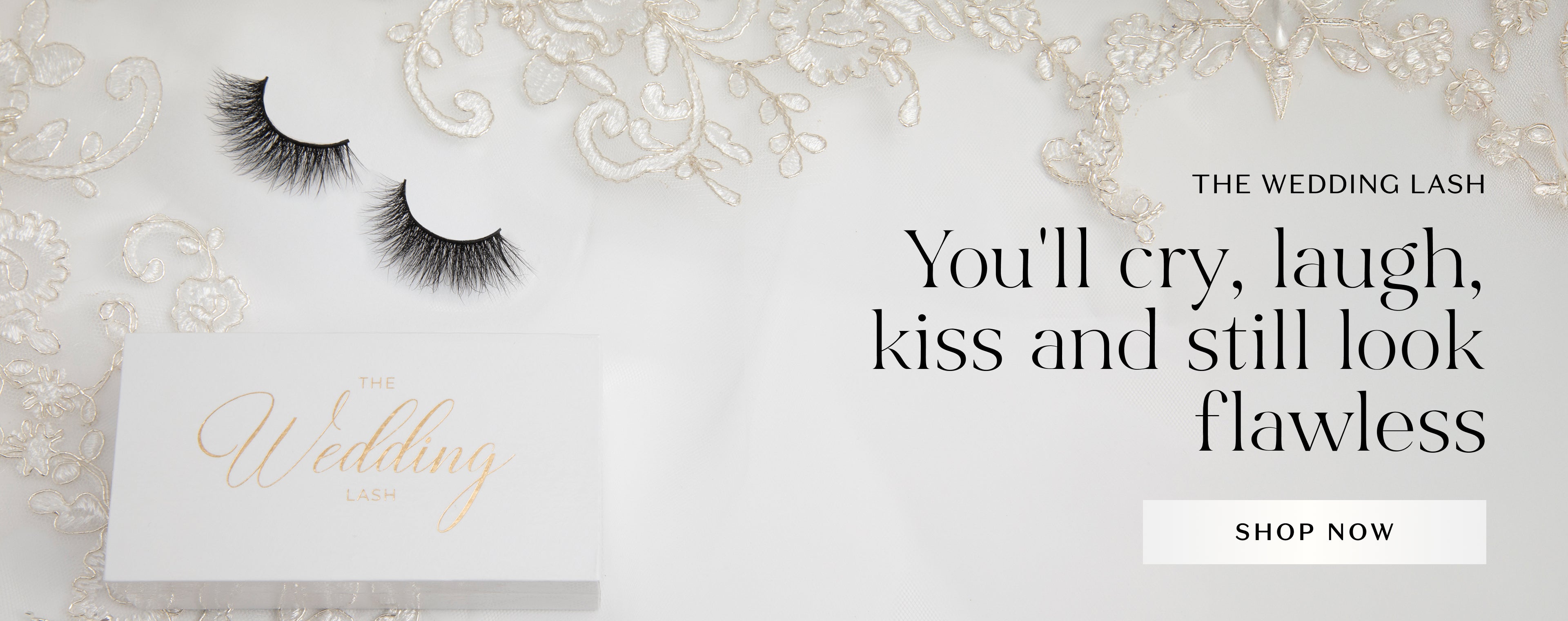 Flat lay of luxurious false eyelashes labeled 'The Wedding Lash' on elegant white lace fabric. To the right, bold black text reads: 'You'll cry, laugh, kiss and still look flawless.' Below the text is a white button with 'SHOP NOW' written on it